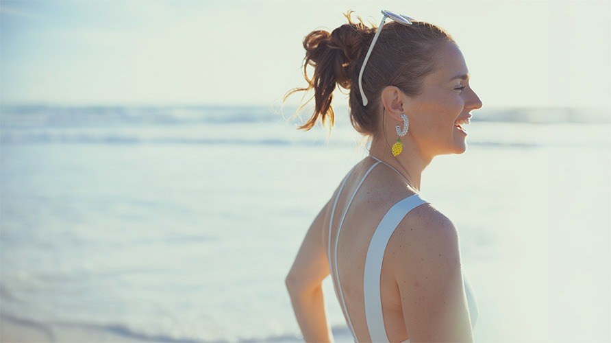 Iloinen nainen seisoo rannalla.