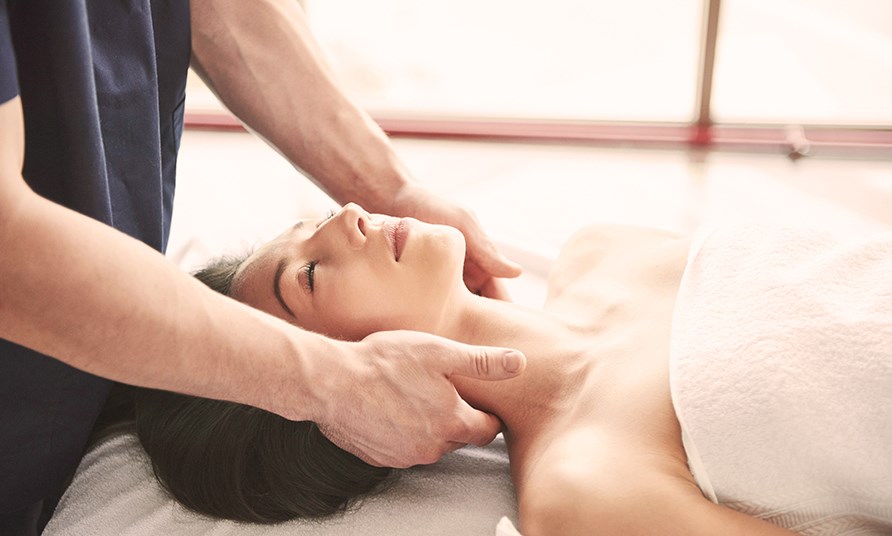 Nainen makaa hierontap�yd�ll� ja saa hell�varaisen lymfahieronnan niskan alueelle.