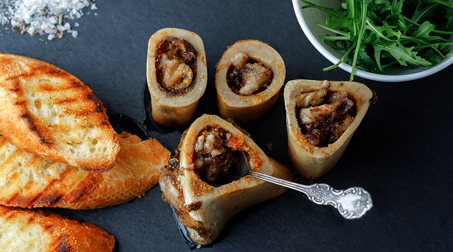 Luuytimi� paahtoleiv�n ja rucolan kera harmaalla p�yd�ll�.